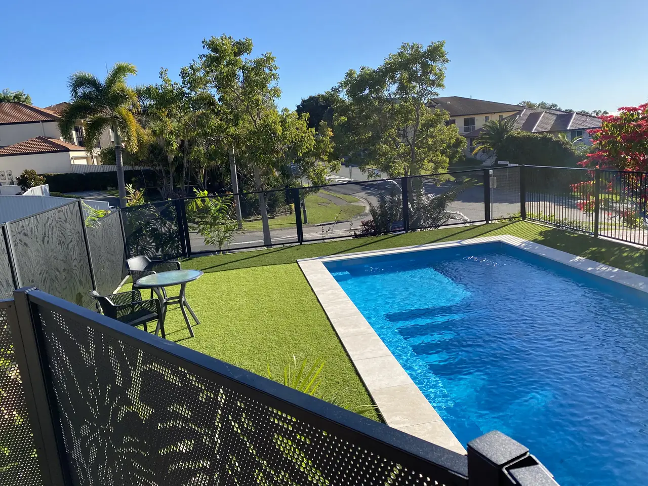 Black Monstera design PoolPerf panels beside a pool and artificial grass in Queensland