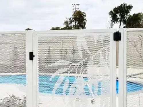 A white PoolPerf fence with one gate carrying a leaf design, around an above ground pool