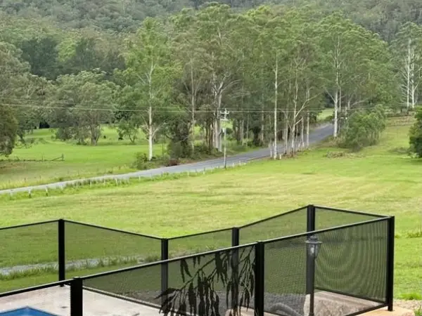 Black perforated panels on sloping ground above a valley, each one cut on an angle to follow the slope