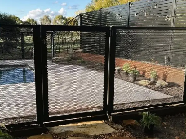 A black PoolPerf gate and fence in front of a black timber slat screen and a pool