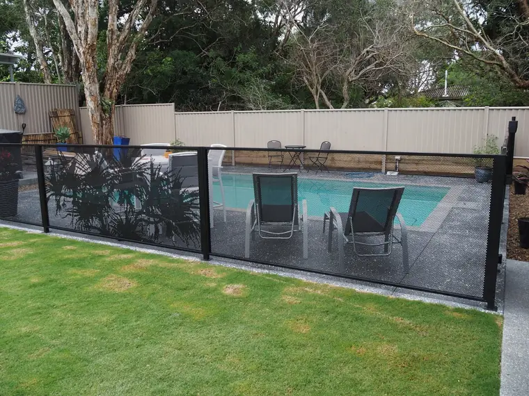 Channel Fit: black PoolPerf panels sitting in channels on the posts, with no brackets showing, beside a backyard pool