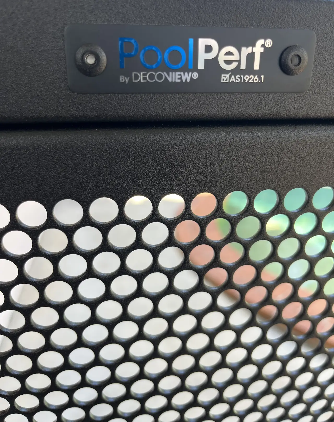 Close up of the PoolPerf plate on the top rail of a black gate, marked By Decoview and AS1926.1, above the perforations
