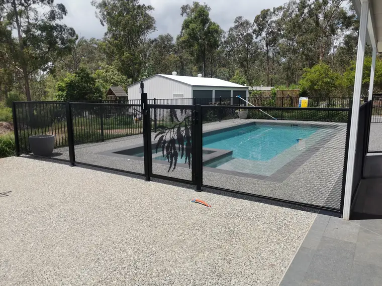 A Monument grey PurePerf pool fence with a Gum design gate beside a pool with a sun shelf