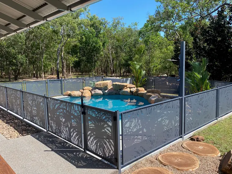 A Pandanus design pool fence and gate in Ironstone around a rock-edged pool in the bush