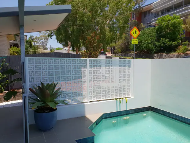 A white Nahosh design pool fence on a white rendered wall above a plunge pool