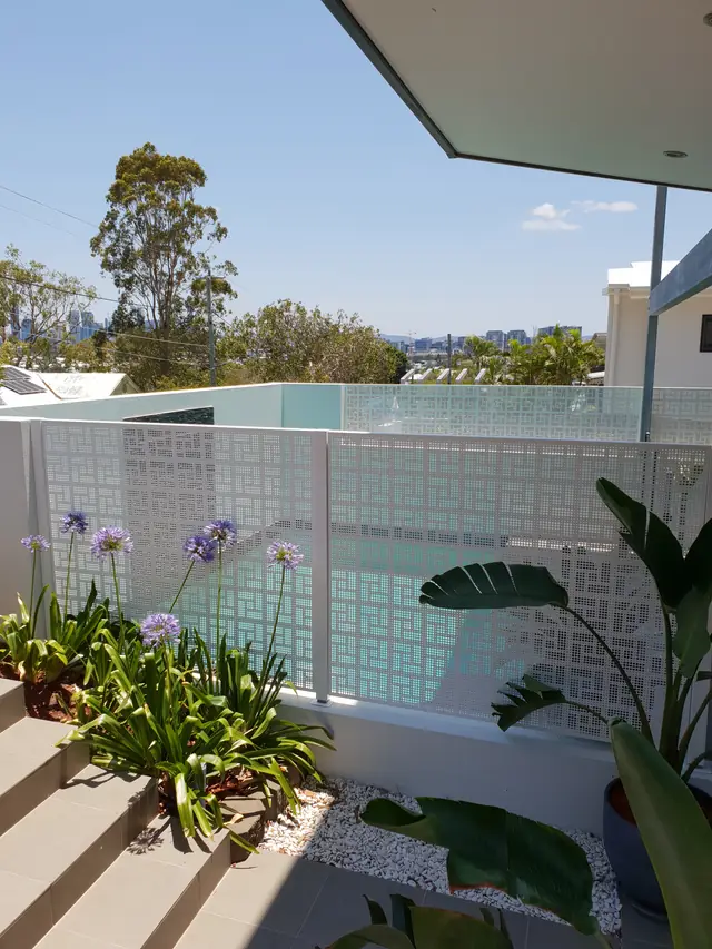 A white Nahosh design pool fence with agapanthus flowering in front of it