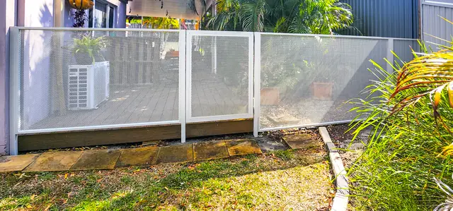 A white Pure Perf fence along a deck, the garden visible straight through it