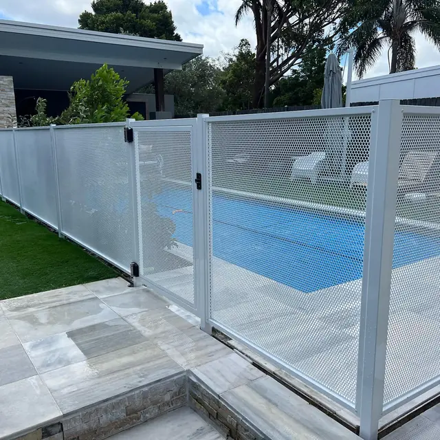 A white Pure Perf pool fence and gate on the edge of a blue pool