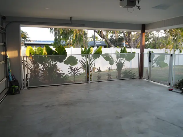 Looking out from a carport through a white Pure Perf fence to a tropical garden