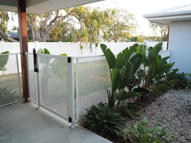 A white Pure Perf pool gate beside a tropical garden bed