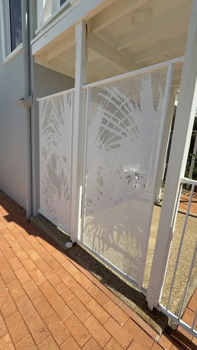 A white Pandanus design gate at the side of a house