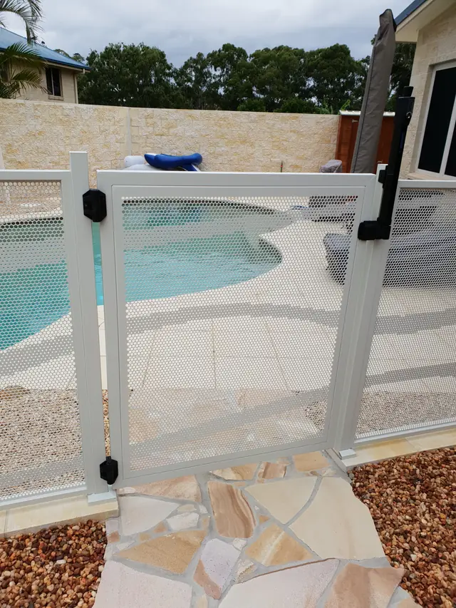 A pale pool gate opening onto a freeform pool