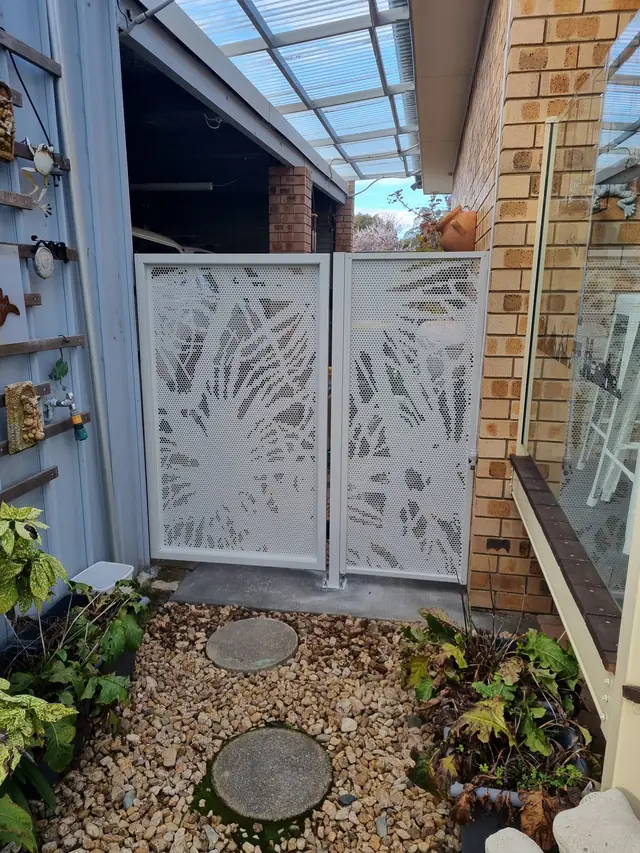 A white Pandanus design side gate between garden beds