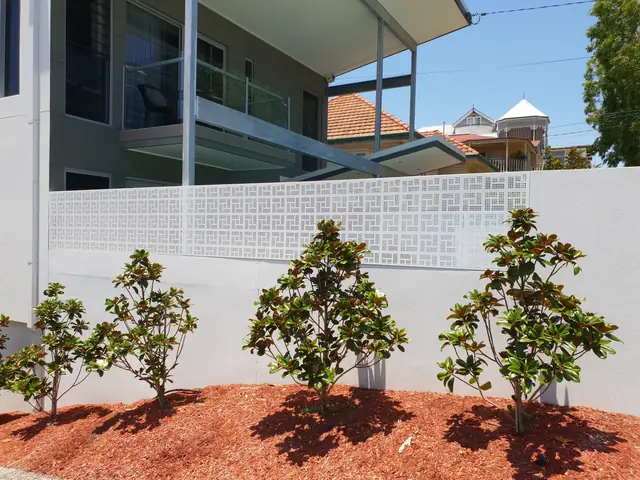 A white Nahosh design screen on top of a rendered wall, with magnolias in front