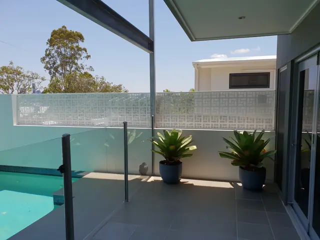 A white Nahosh design screen above a pool and glass fence