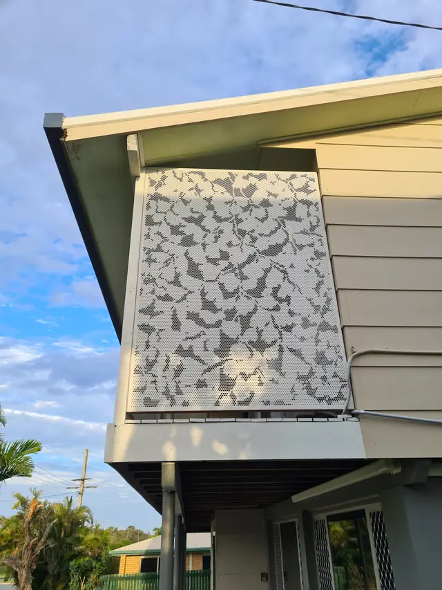 A white leaf-pattern screen on the side of a house