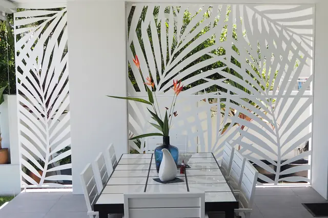 White Palmy design screens either side of an outdoor dining table