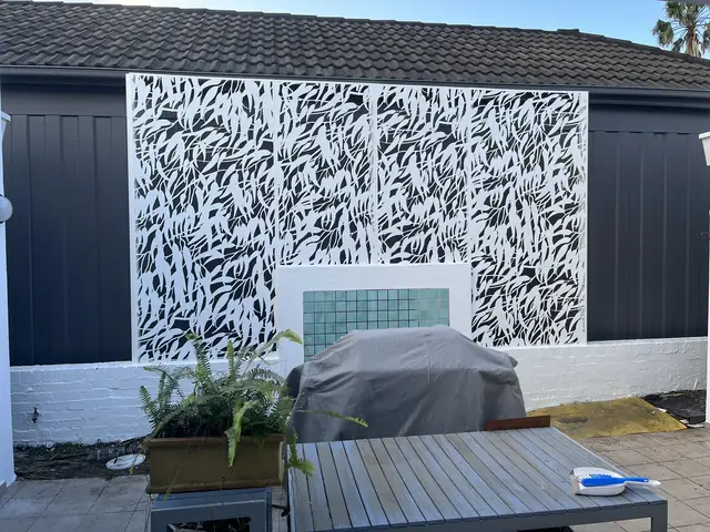 A white Gum design screen on a dark wall behind a barbecue