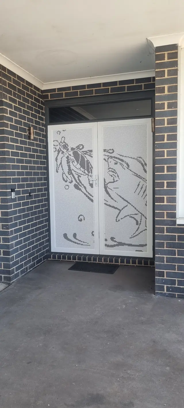A white custom-design security screen door at a front entry
