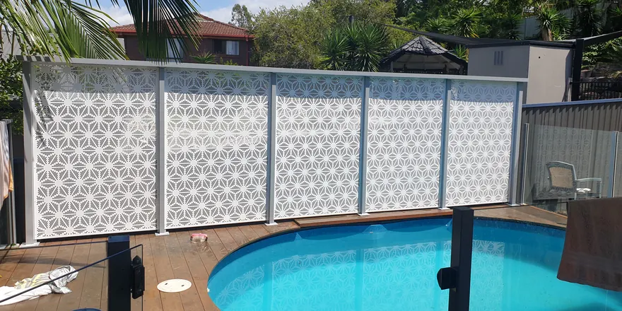 A white PoolPerf pool fence around a round in-ground pool