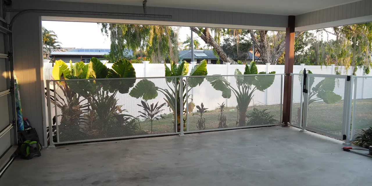 Looking out from a carport through a white Pure Perf fence to a tropical garden